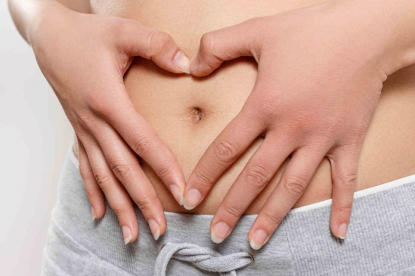 Woman’s hands over early pregnant stomach